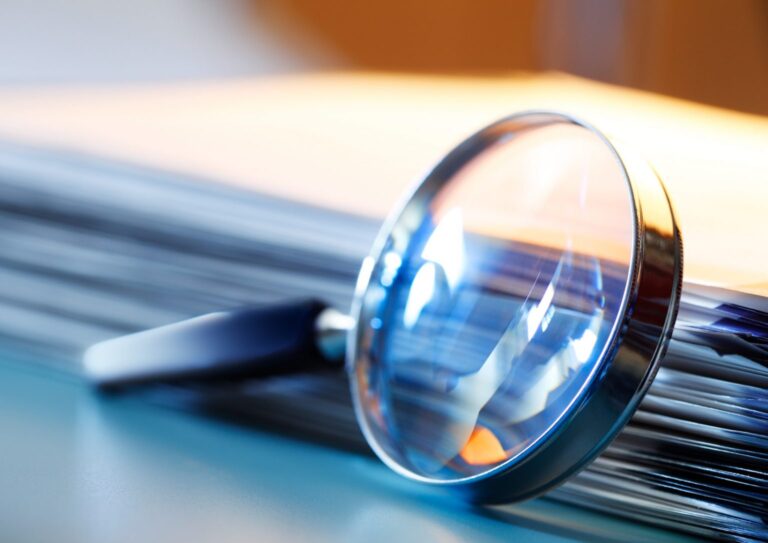 magnifying-glass-leaning-against-stack-of-papers