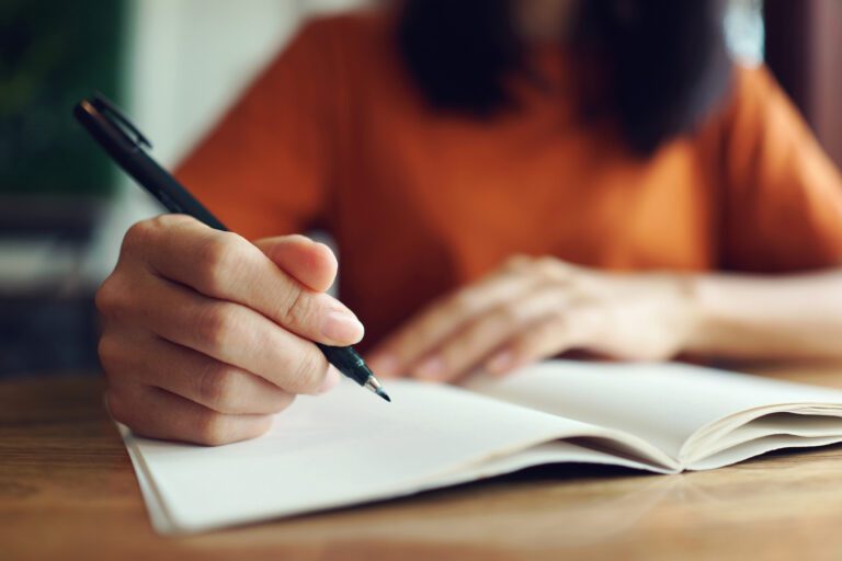 Close up woman hand writing on notebook .