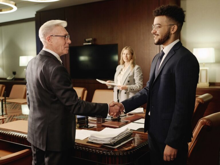 caucasian-and-middle-eastern-men-shaking-hands-standing-in-office-boardroom Bridging the Generational Divide for More Effective Law Firm Governance